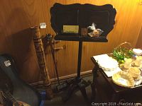 Overall view showing the two string instruments leaning against the wall beside a solid wood sheet music stand.