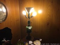 Photo showing the antique lamp fully lit with two bulbs in side sockets and one bulb in front, top torchiere is missing a bulb.