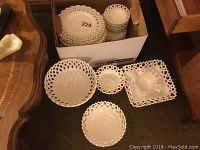 36 pieces of white milk glass dinnerware with reticulated/openwork rims shown in a box and displayed on floor including plates, bowls, and footed dishes.