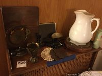 Wide view of all items in the lot showing the scale, pitcher on wooden base, metal decor, and the bronze gong