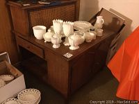 Full view of the Bodart wooden cabinet showing caned top, drawers, and white decorative items on top