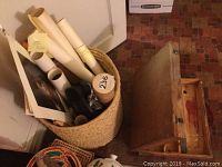 Basket with rolled prints and an artist box, next to a wooden box