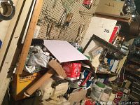 Wide view of workshop showing boxed hardware, tools, wood pieces, and storage shelves with assorted tools and hardware.