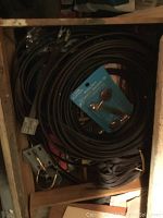 A photo showing several coiled black cables or hoses, and some mounting hardware packaged in plastic on blue cardboard.