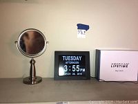 Photo showing American Lifetime digital day clock with day, time, date on screen, and the stainless steel framed two-sided vanity mirror on pedestal stand.