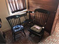 Three vintage black wooden chairs by Nichols and Stone including one rocking chair with floral detailing and two stationary chairs