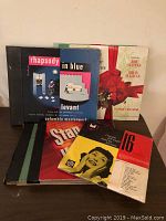 Seven vintage vinyl record sets arranged overlapping with visible titles including Rhapsody in Blue, Stanton Kenton, String Time, and Firestone Christmas Favorites.
