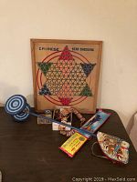 Overall view of the vintage toys lot showing Chinese Checkers board, spinning top, wooden bead necklaces, pull-string toy, and packaged cards