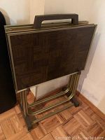 Photo of vintage TV trays nested in metal stand with visible wood pattern, showing overall condition and tray design