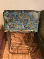 Photo showing a single TV tray with colorful circular pattern resting on metal frame stand