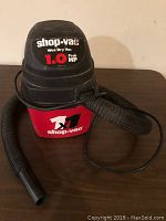 Front view of Shop-Vac brand wet/dry vacuum showing red and black body with flexible hose attached, clear Shop-Vac label with 1.0 Peak HP.