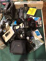 Overview of vintage cameras, film, tripod in box, bags and accessories laid out on table