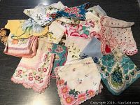 Top view of assorted vintage handkerchiefs showing various colorful floral patterns and scalloped edges.