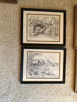 Two framed black and white prints hung on a wall, showing urban and botanical scenes of Sydney with black frames and white mattes.