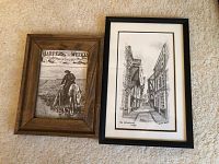 Two framed prints shown side by side on carpet: left is Harpers Weekly print in wooden frame, right is Brian Lewis signed print titled 'The Shambles New York' in black frame.