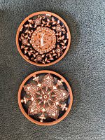 Two round Greek wall plates with terracotta and black intricate floral and animal designs.