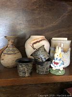 Front view of all pottery items, napkin rings and bunny figurine on wooden shelf.