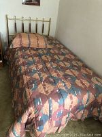 Full view of twin bed with bedding and headboard.