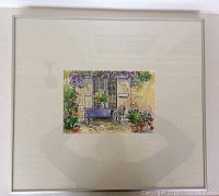 Framed painting with mat and white frame, showing a garden patio scene with bench, chair, plants, and stone wall.