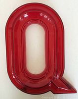 Photo of red marquis letter Q showing front face and overall shape.