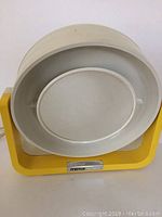 Front view of the vintage makeup mirror showing the oval mirror inside white frame with yellow base and 'mirror by Clairol' label