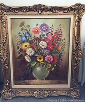 Full view of the ornate framed oil painting showing colorful flowers in a green vase.