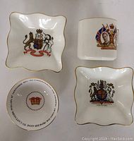 Overview of four vintage English bone china pieces including two square dishes, a cup, and a small round dish. Each has gold trim and royal commemorative designs.