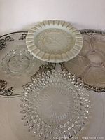Lot of four vintage trays including two silver overlay trays, one clear divided tray, and one white zodiac-themed tray