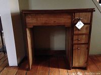 Wooden sewing cabinet closed, showing front with drawers and door on the right.