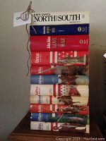 Stack of hardcover books with titles showing the complete Kent Chronicles eight volumes and the three North and South trilogy books by John Jakes. Dust jackets present on most, with some visible wear.