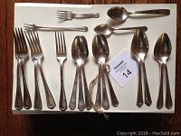Full view of 12 vintage forks and spoons laid out on white surface, showing overall condition and quantity