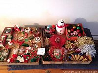 Full view of two cardboard trays filled with a variety of Christmas ornaments including balls, string decorations, and figurines.