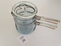 Blue-tint glass double boiler pot stacked with clear glass lid on top, showing the handle and stainless steel band.