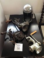 All four vintage kitchen tools shown on black table including juicer, apple peeler, Universal Food Chopper grinder, and English stamped grinder.