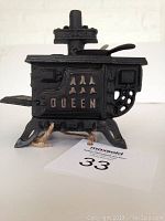 Front side view showing vintage cast iron Queen stove with the oven door closed and detailed legs.