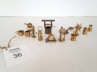 Full view of the brass and metal miniatures lined up in a row, showing detailed craftsmanship and including various types of vessels and a ship's wheel.