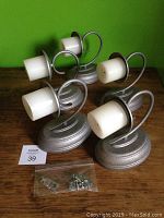 Five matching candle effect wall sconces with silver oval bases, curving arms, and white cylindrical candle lights, displayed on wooden surface with mounting hardware in plastic bags.