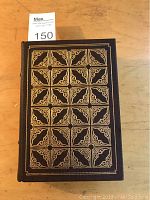 Front cover of the book showing black leather with intricate gilt tooled designs.