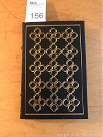 Front cover of the book showing black leather with gilt geometric pattern and design.
