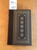 Front cover of the book showing black leather binding with gold gilt intricate decoration.