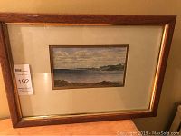 Full view of framed watercolour painting showing the entire antique oak frame and mat with the coastal landscape scene inside.