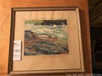 Framed serigraph silkscreen river scene by Joseph Earnest Sampson on wooden surface.