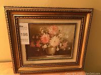 Full view of floral still life painting framed in ornate gilt wood frame.