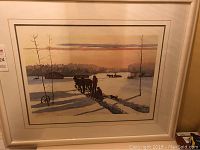 Framed and matted print of a winter landscape depicting two horses pulling a sled with figures and a dog, signed by Allen Sapp, with visible certificate of authenticity.
