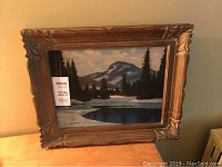 Full view of oil painting in carved wood frame showing winter landscape with mountains and water reflecting sky