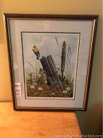 Framed signed limited edition print of two yellow birds on a wood post among wildflowers.