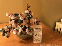 Full view of the Chinese Peking Glass jade tree with pink blossoms in celadon pot on wooden table.