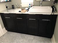 Full front view of dark wood vanity with white marble top and rectangular sink