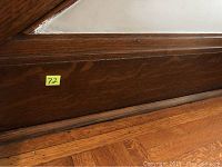 Close-up of a ten inch oak base board section showing wood grain and finish with a yellow lot number sticker attached.