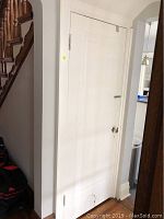 Full view of a white painted interior door with a semi-circular cat door cut-out at the bottom installed in a white door jamb.